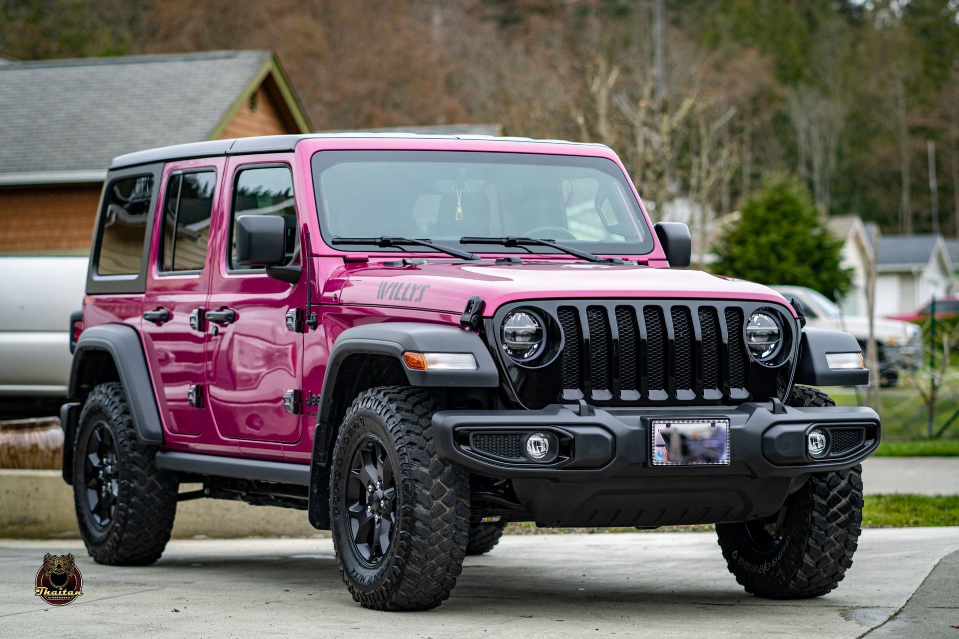 A pink jeep is parked in a driveway in front of a house.