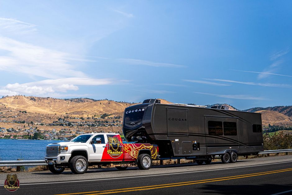 A truck is towing a rv down a road.