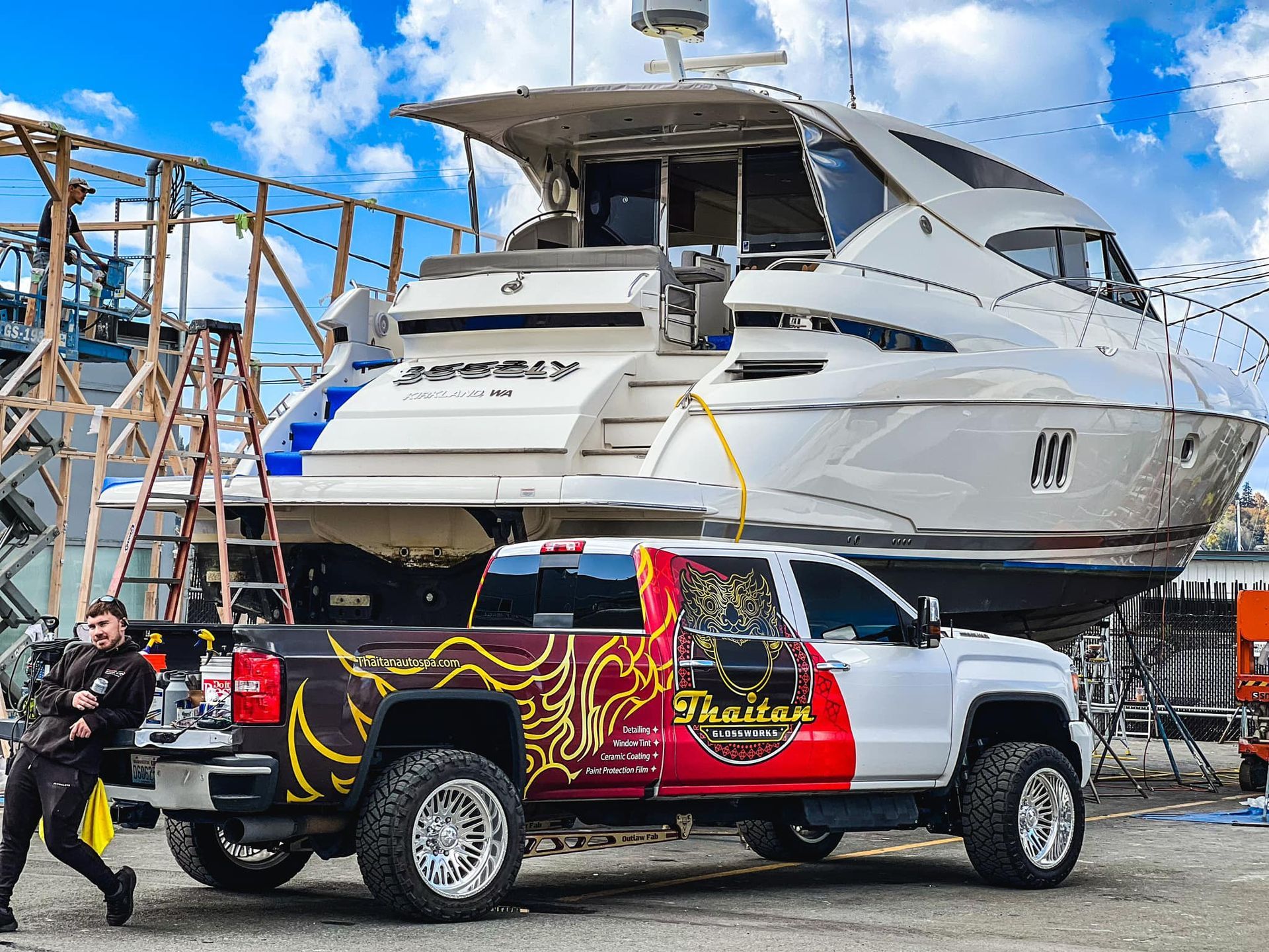 A man is standing next to a truck with a boat on top of it.