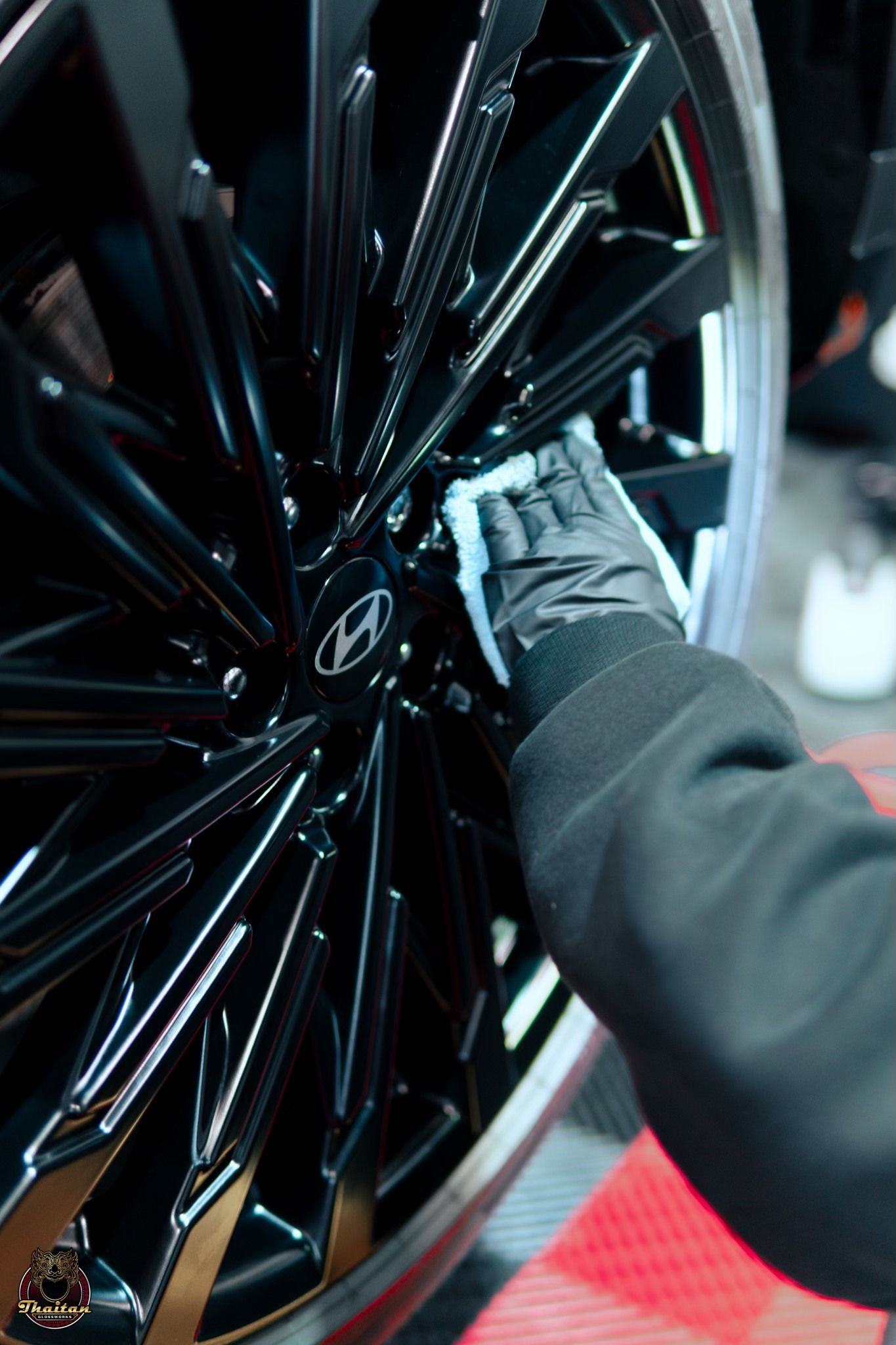 A person is cleaning a car wheel with a cloth.
