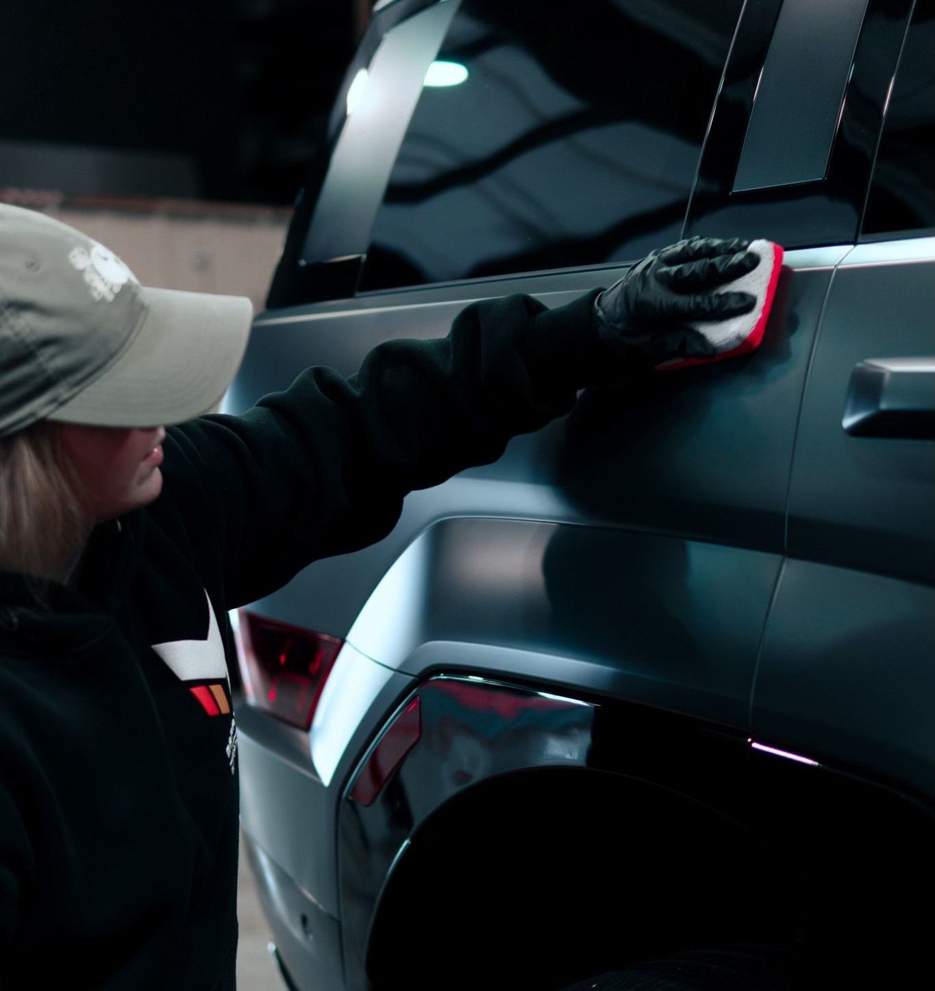 A woman is cleaning a car with a sponge