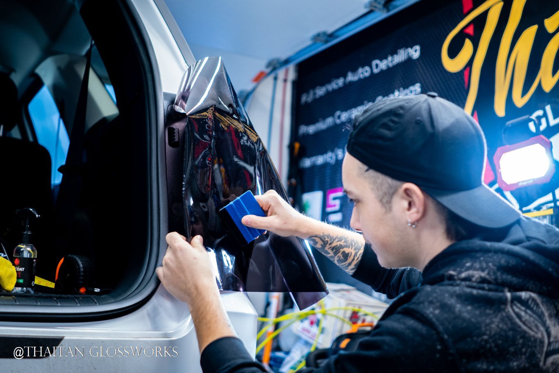A man is applying tinted glass to the back window of a car.
