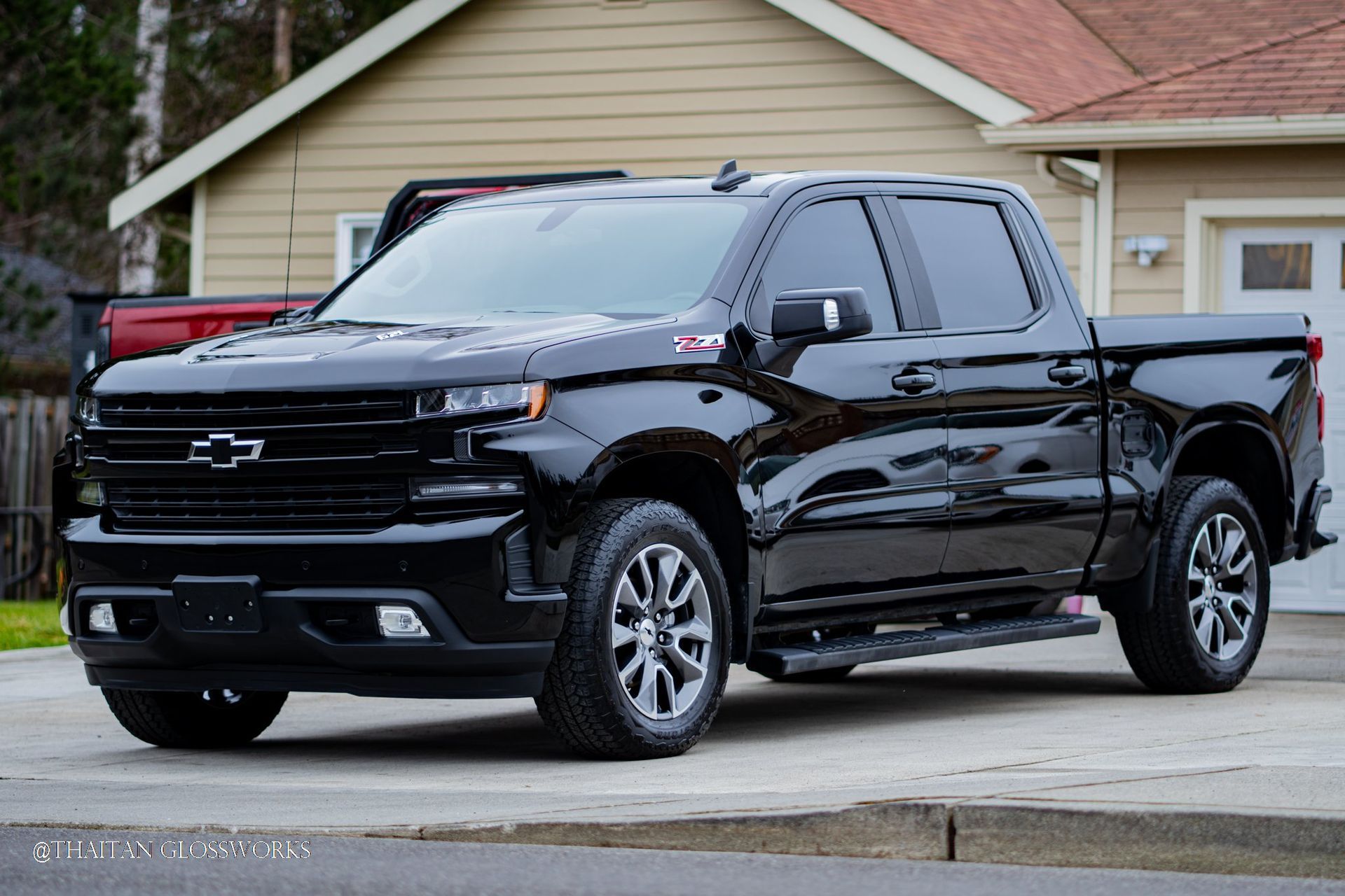 Window tint on a black pickup truck is parked in front of a house.