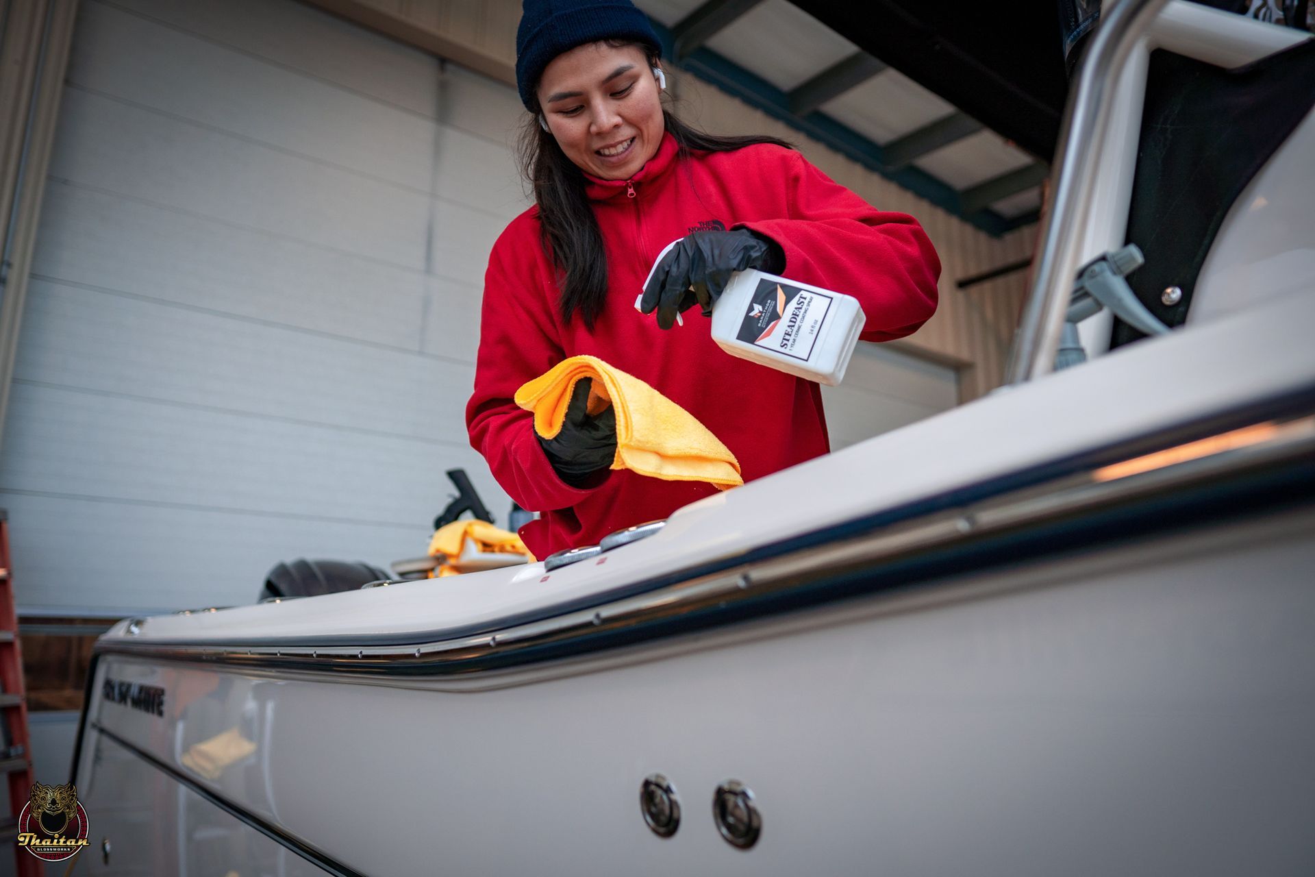 A woman is cleaning a boat with a towel and a spray bottle.