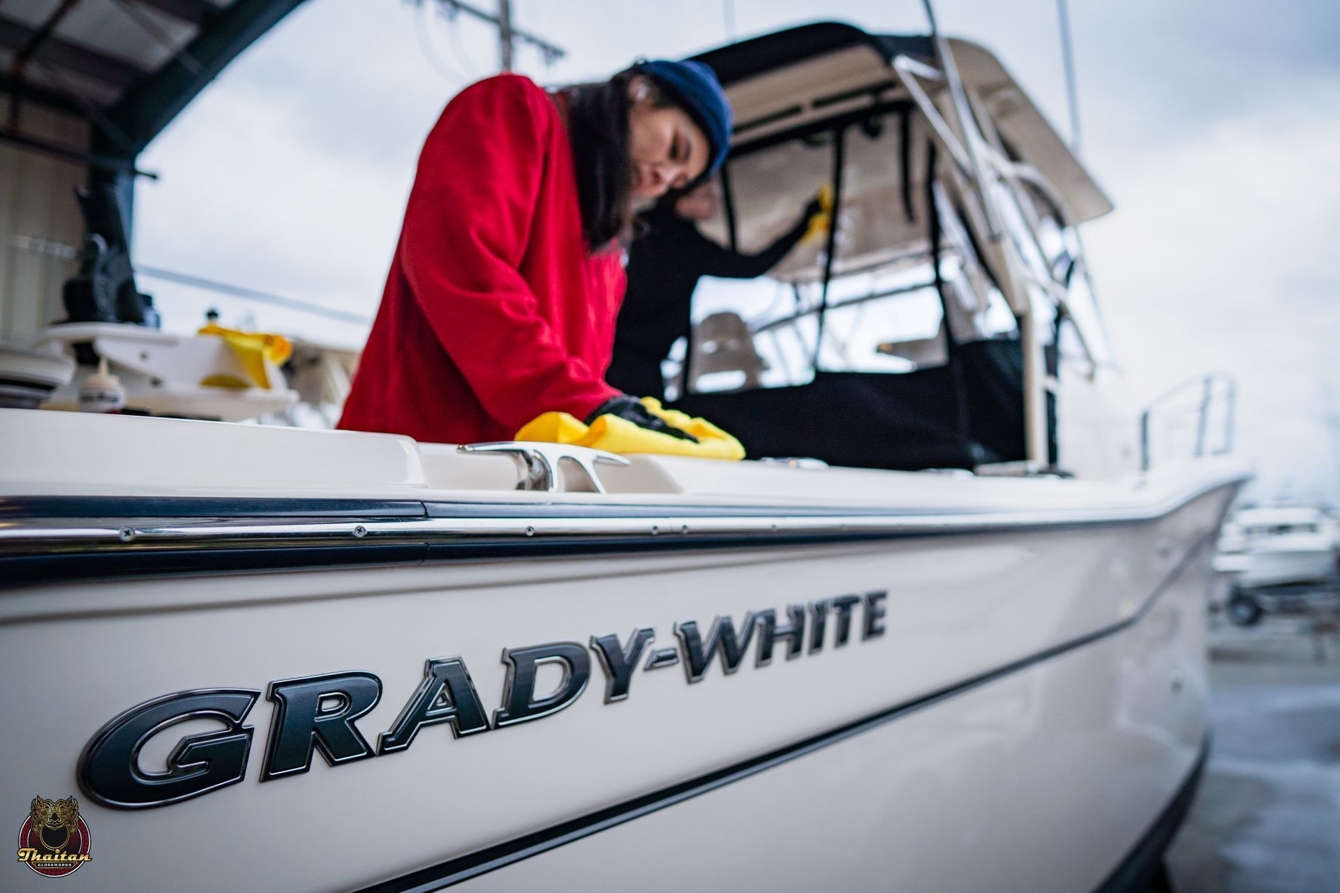 A woman is cleaning the side of a boat that says grady-white