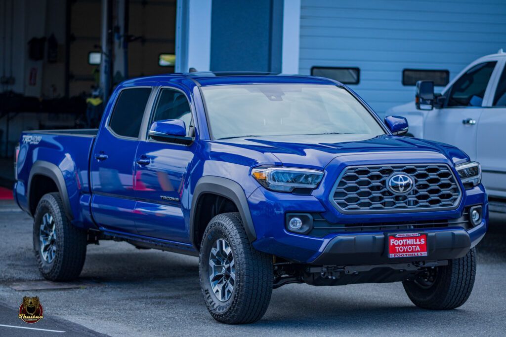 A blue toyota tacoma truck is parked in front of a building.