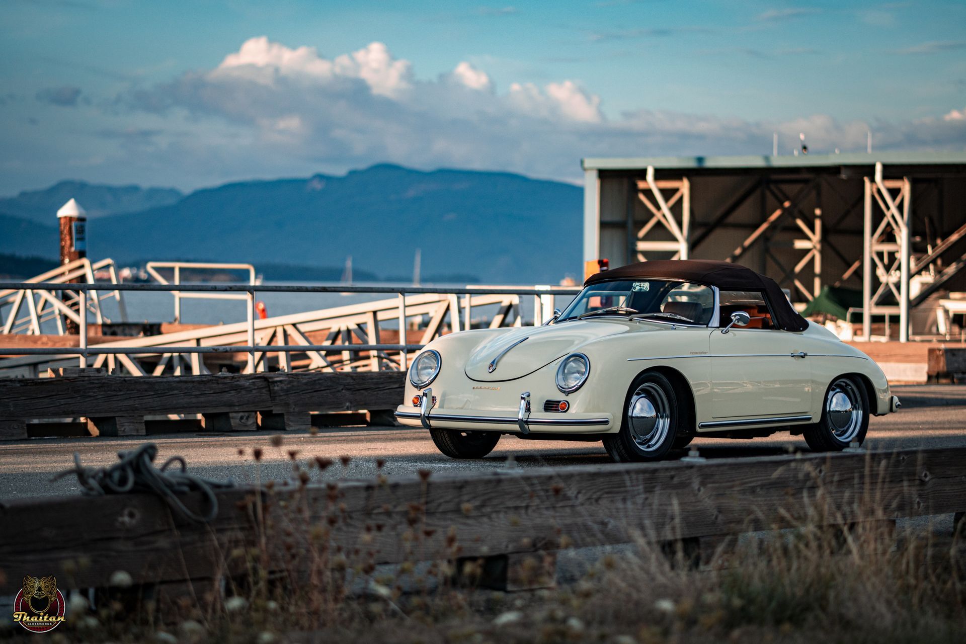 A white porsche convertible is parked on the side of the road in front of a building.