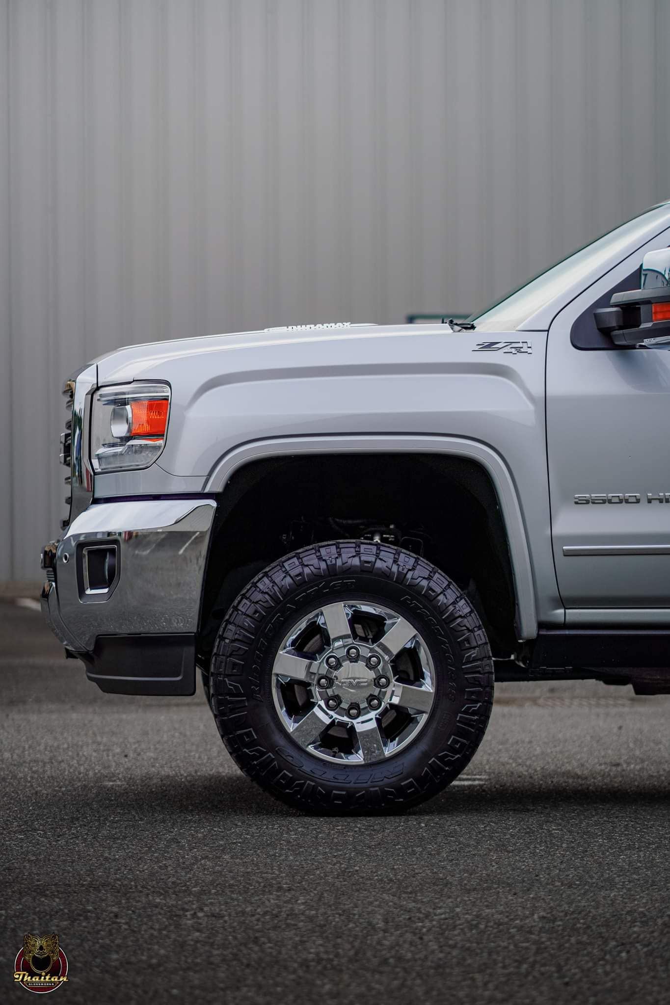 A white truck is parked in front of a white wall.