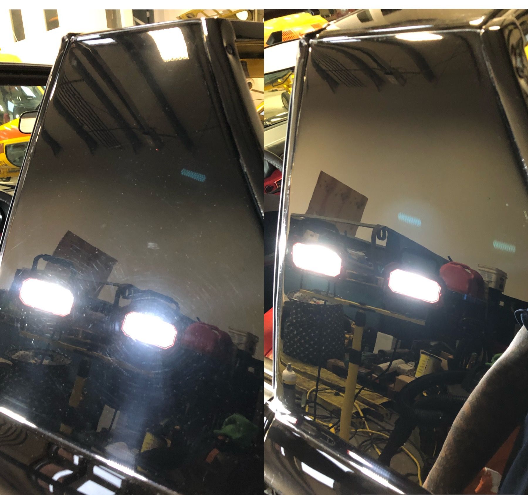 A man and a woman are polishing a black truck in a garage.