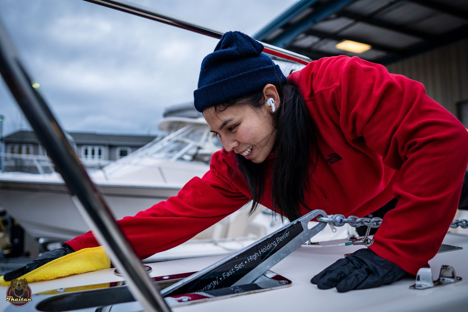 A woman in a red jacket is working on a boat.