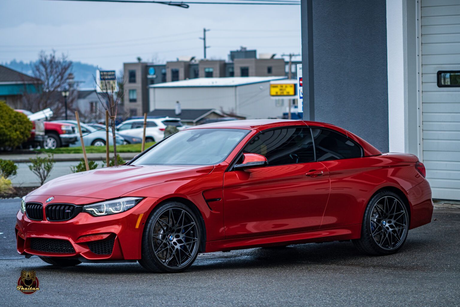 A red bmw m4 is parked in front of a garage door.