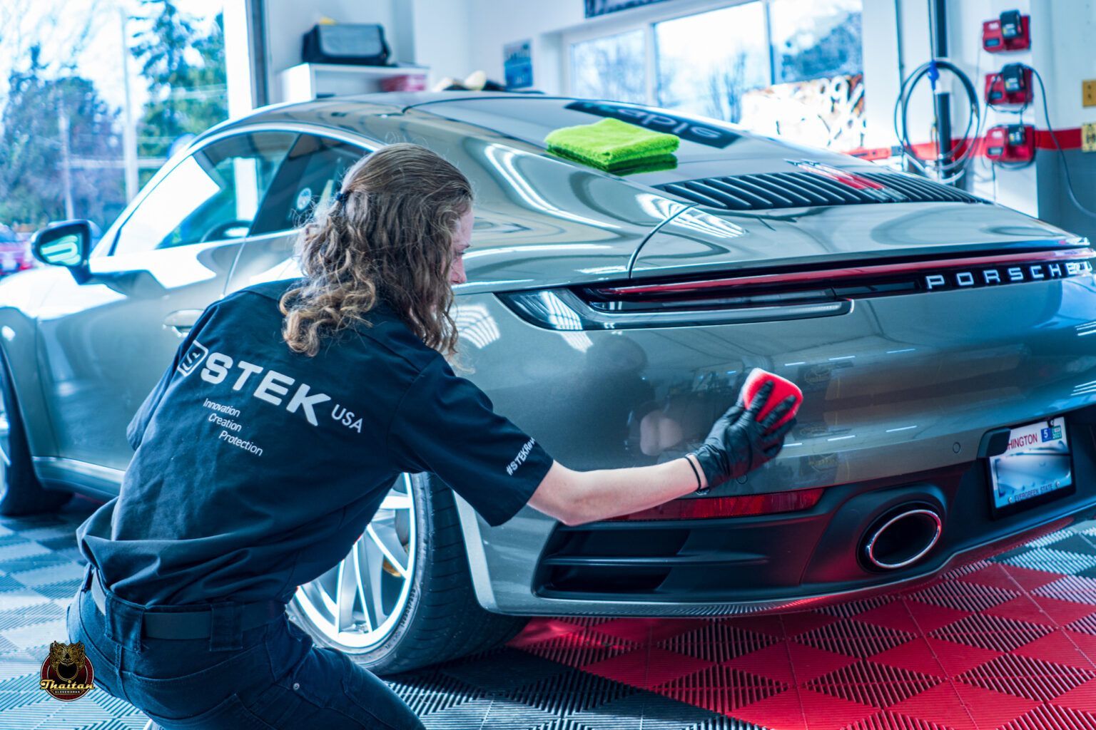 A woman is cleaning the back of a porsche 911.