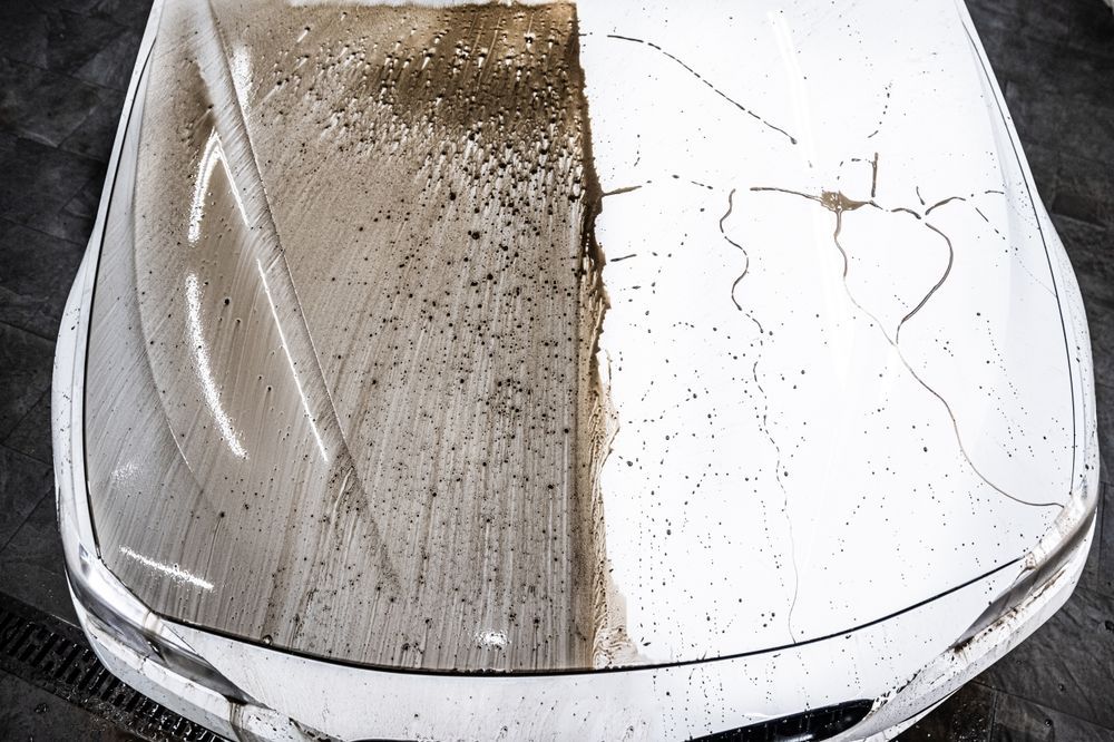 A white car with a dirty hood and a clean hood.