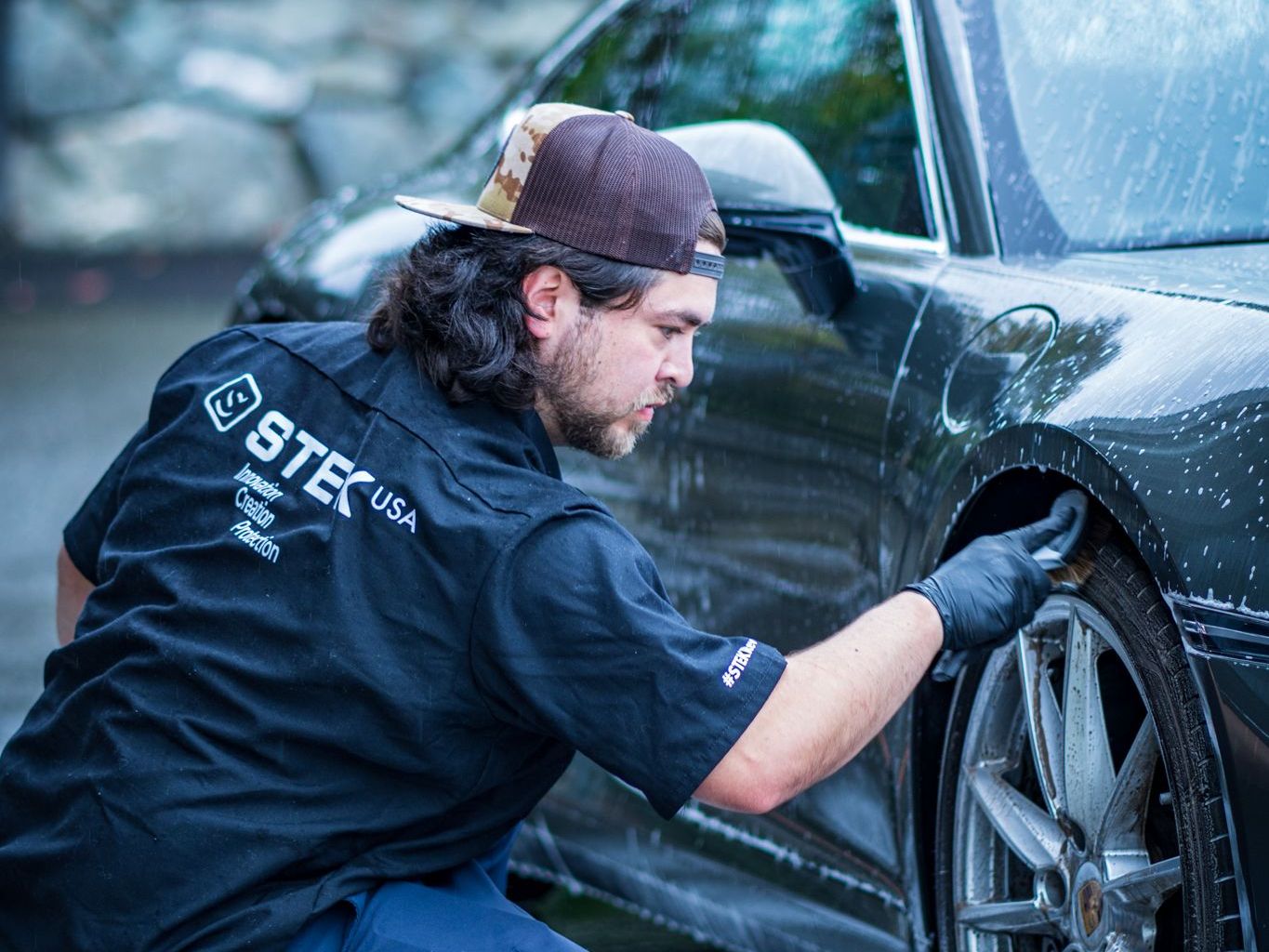 A man in a black shirt is washing a car.