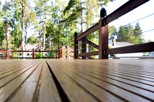 A wooden deck with a fence and trees in the background