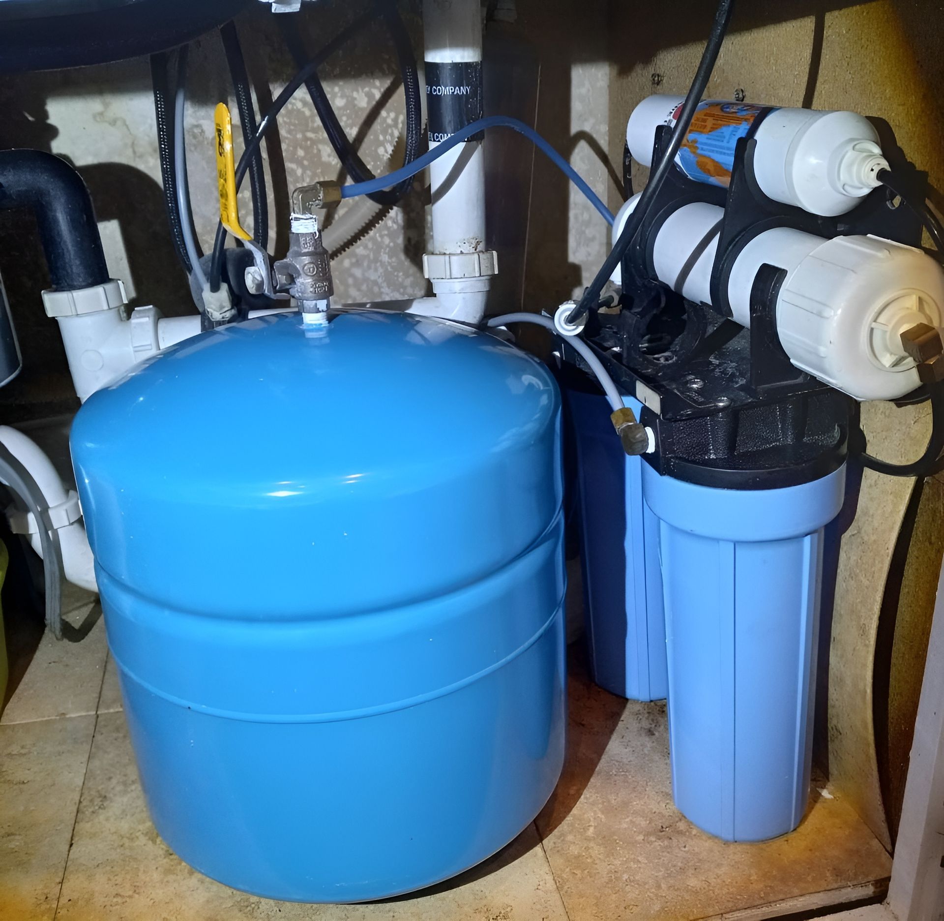 A blue water tank sits under a kitchen sink