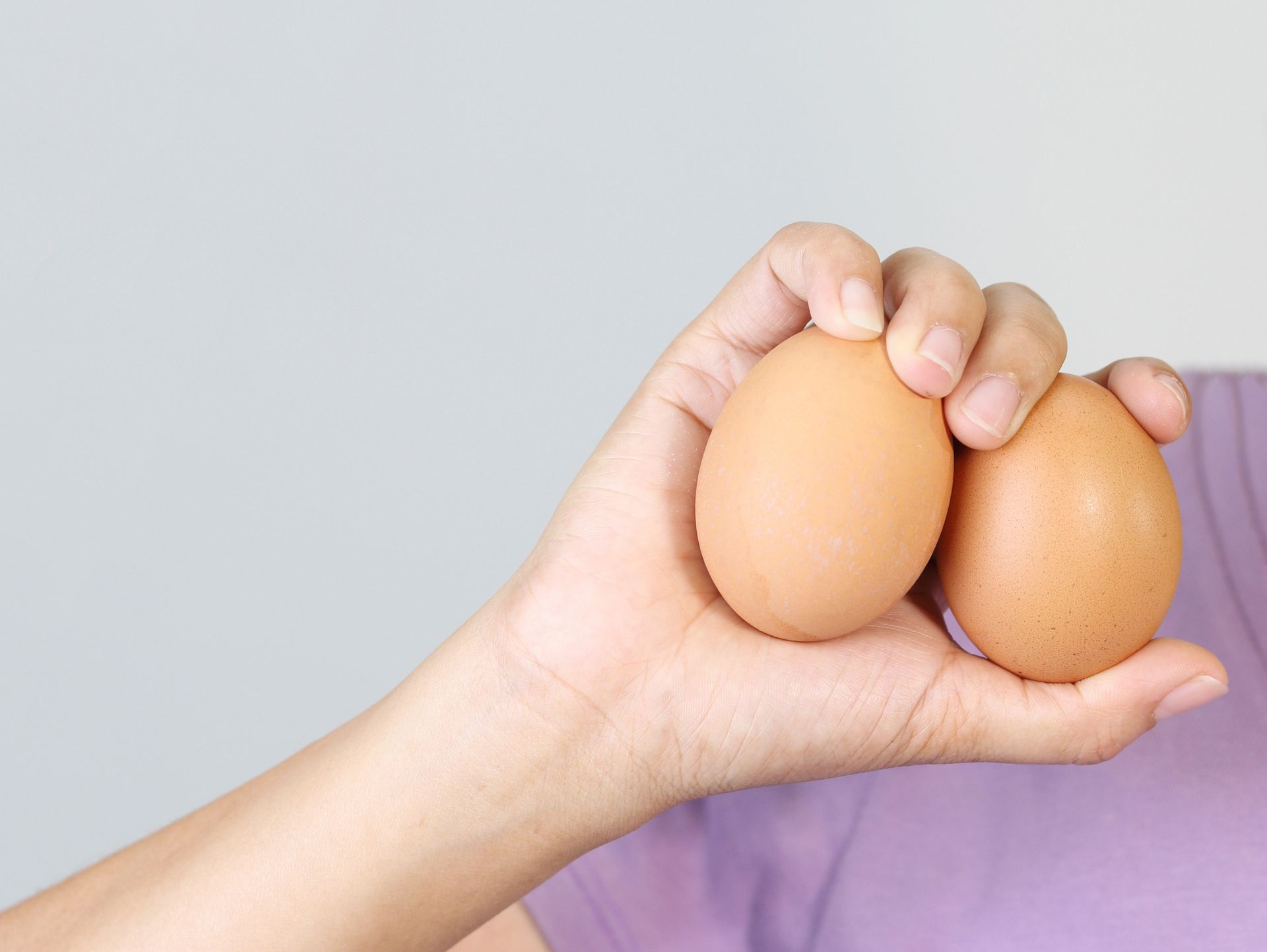 Mano che tiene due uova marroni.