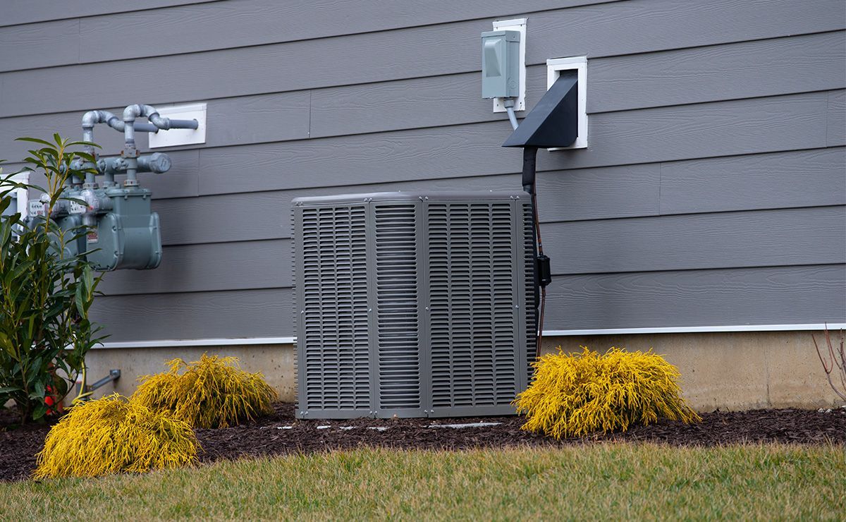 An air conditioner is sitting on the side of a house.