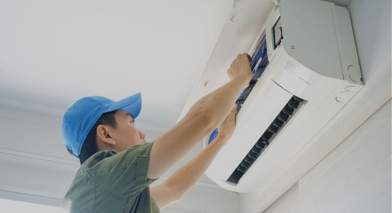 A man is fixing an air conditioner on the wall.