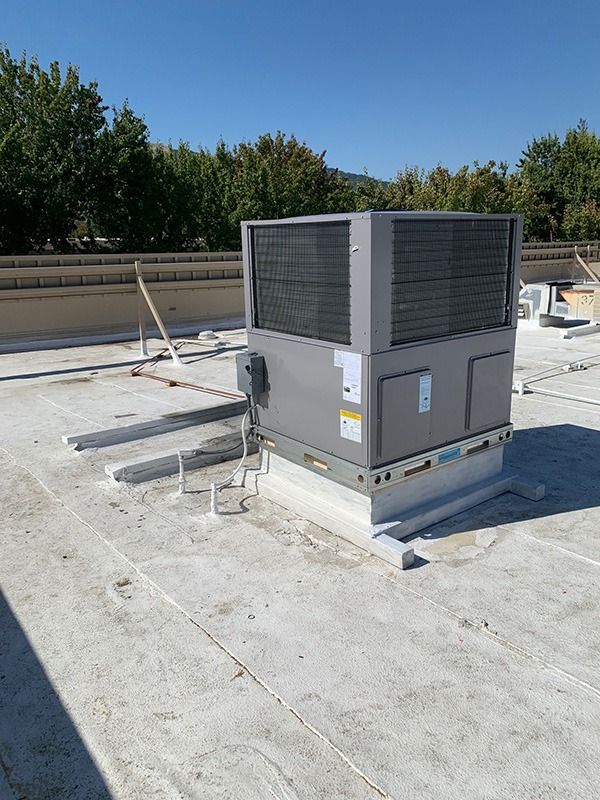 A large air conditioner is sitting on top of a roof.