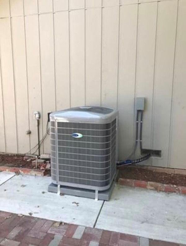 A Carrier air conditioning is sitting on the side of a building.