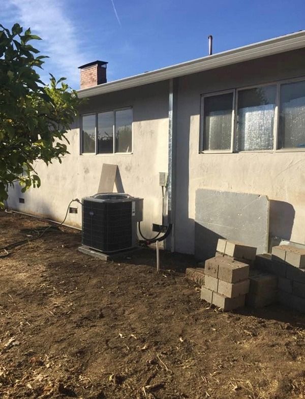 A backyard of a house with a black air conditioner