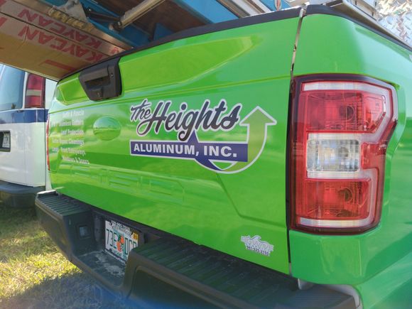 A green truck with a sticker on the back that says `` the heights aluminum inc. ''