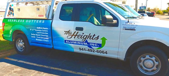 A white and blue aluminum truck is parked in a parking lot.