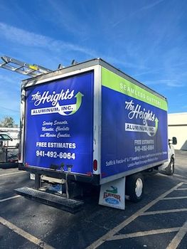 A blue and green truck is parked in a parking lot.