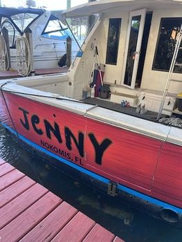 A red boat with the name jenny on the side is docked at a dock.