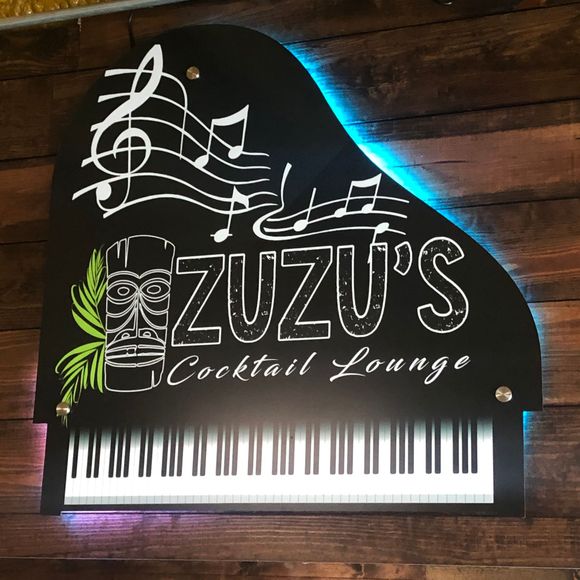 A piano shaped sign for zuzu 's cocktail lounge