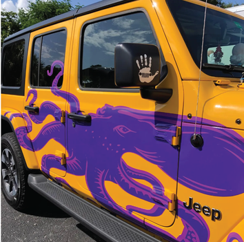 A yellow jeep with purple octopus painted on the side