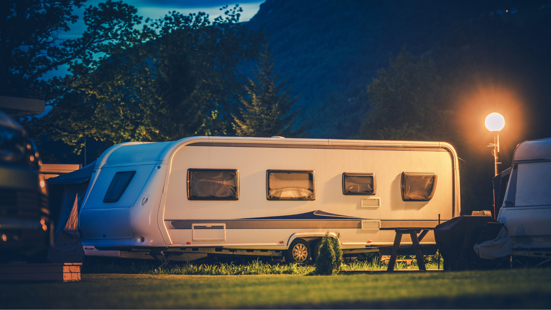 A caravan is parked in a grassy field at night.