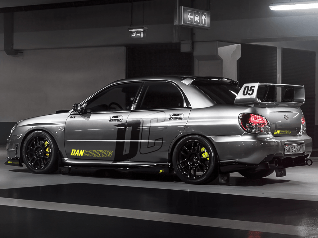 Um subaru wrx sti prateado está estacionado em uma garagem.