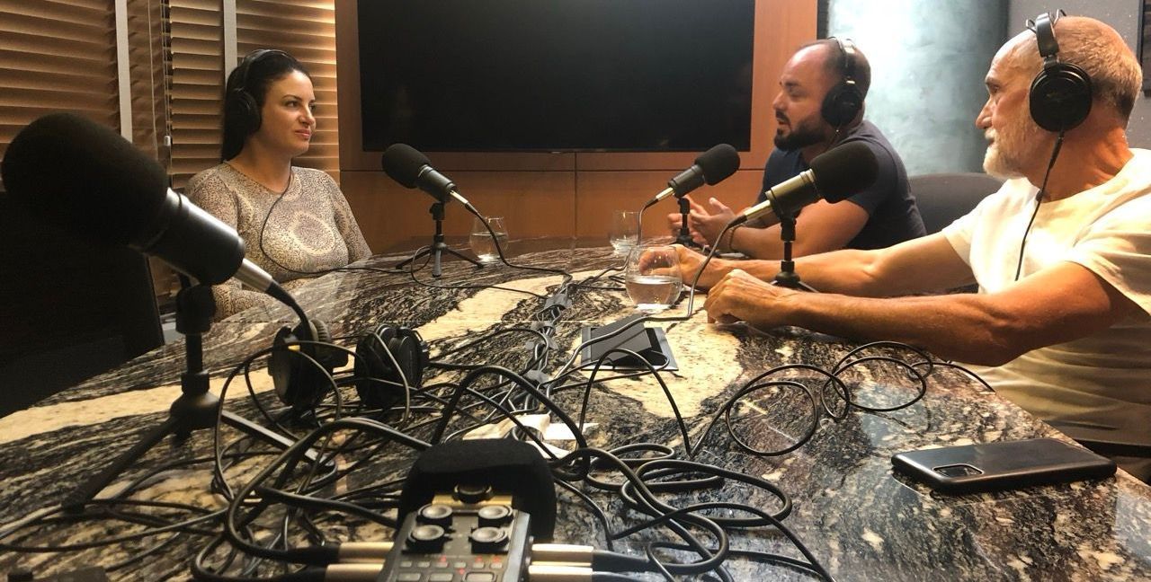 A group of people are sitting at a table in front of microphones.