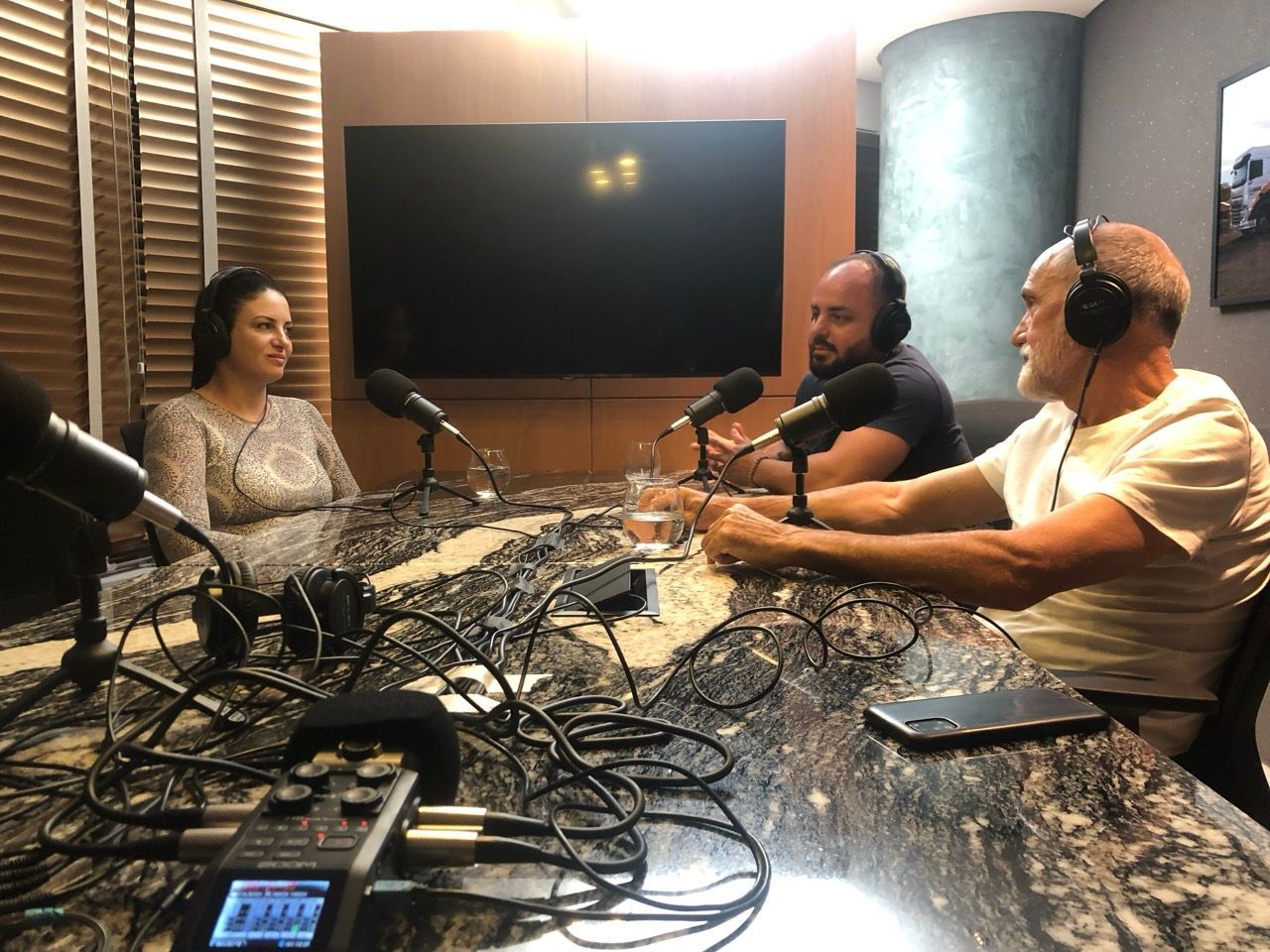 Um grupo de pessoas está sentado em uma mesa com microfones.