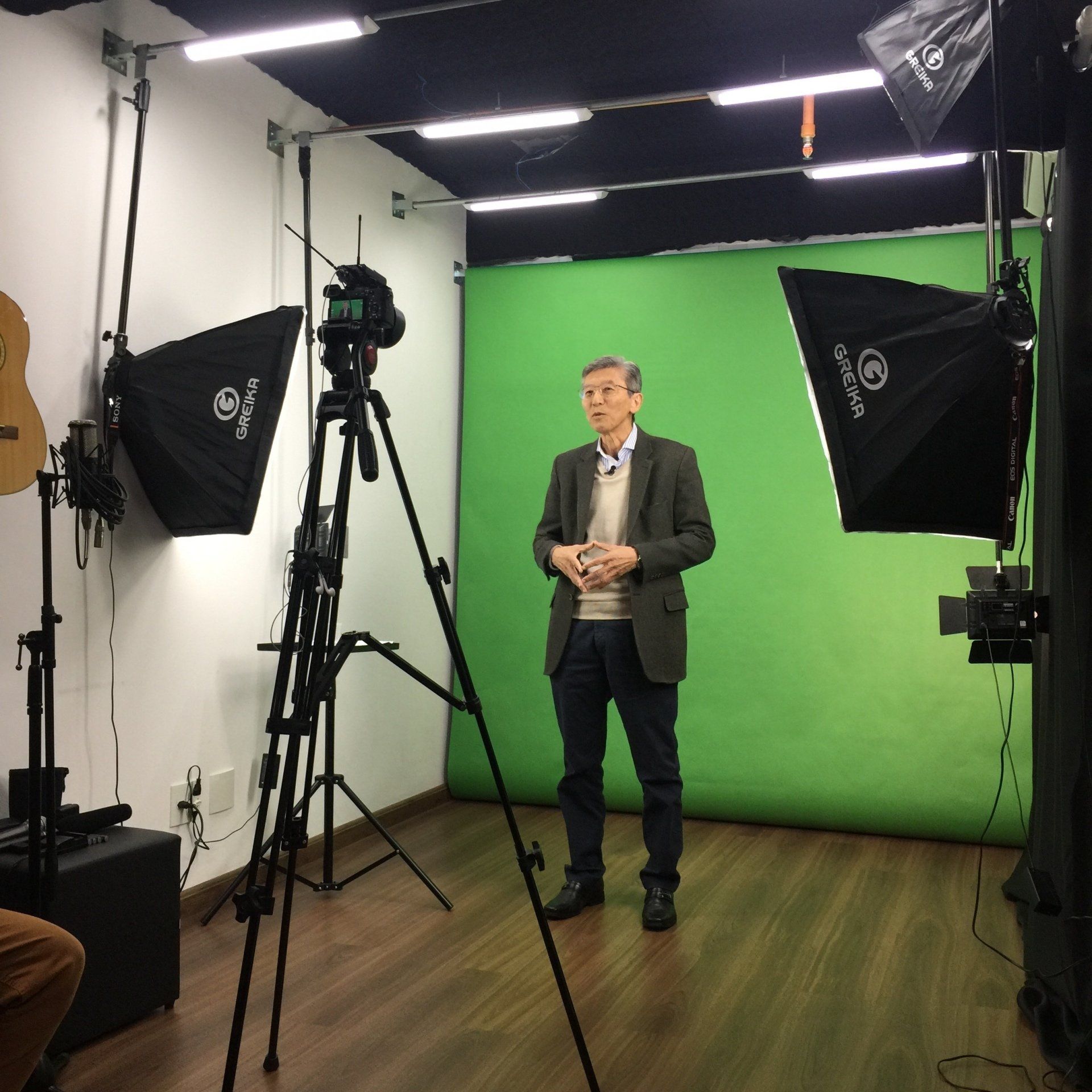 Um homem de terno está parado em frente a uma tela verde