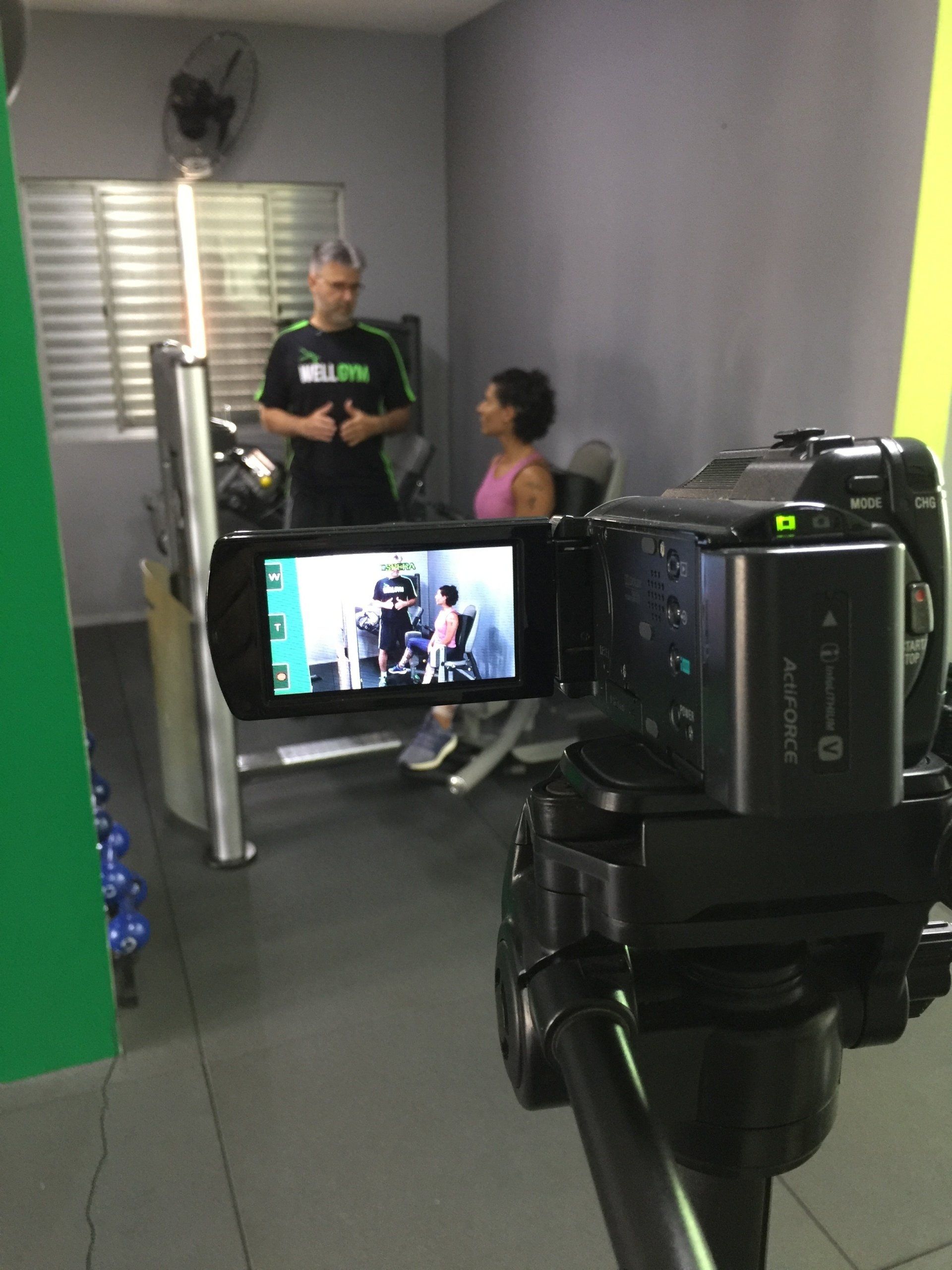 Uma câmera está gravando um homem e uma mulher em uma academia