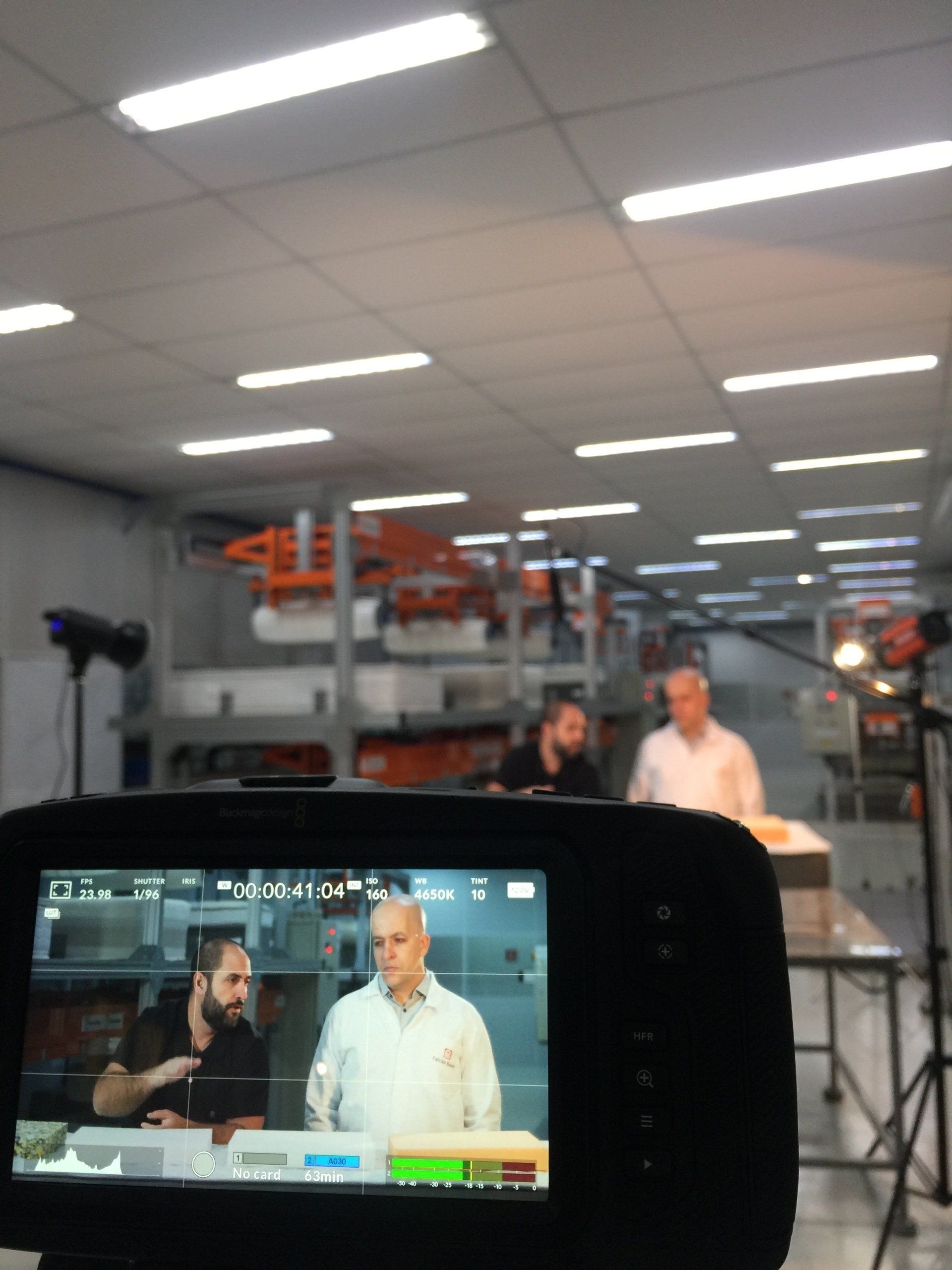 Uma câmera mostra um homem conversando com outro homem em uma sala