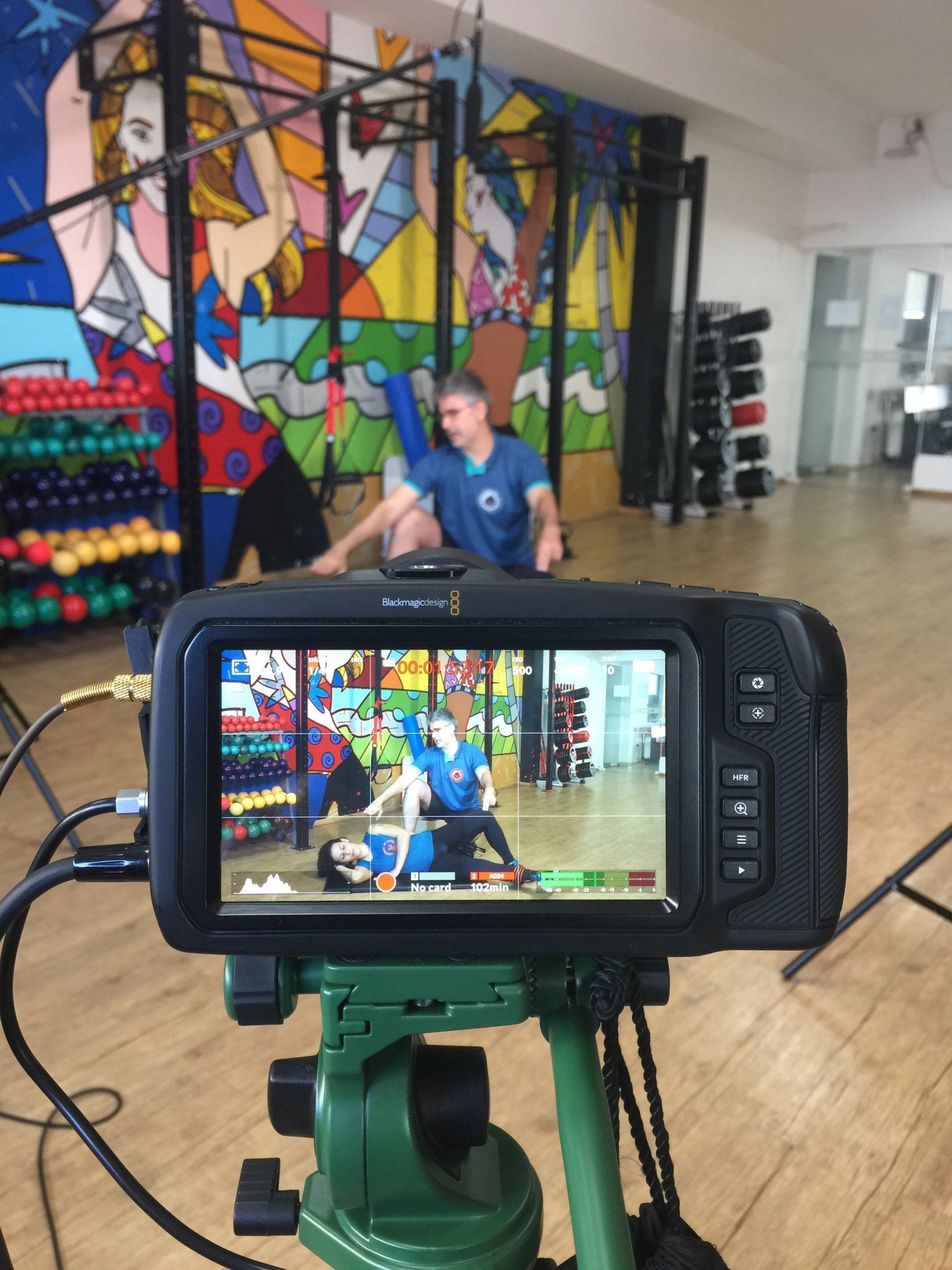 Uma pessoa vestida de azul filmando outra pessoa se exercitando. 