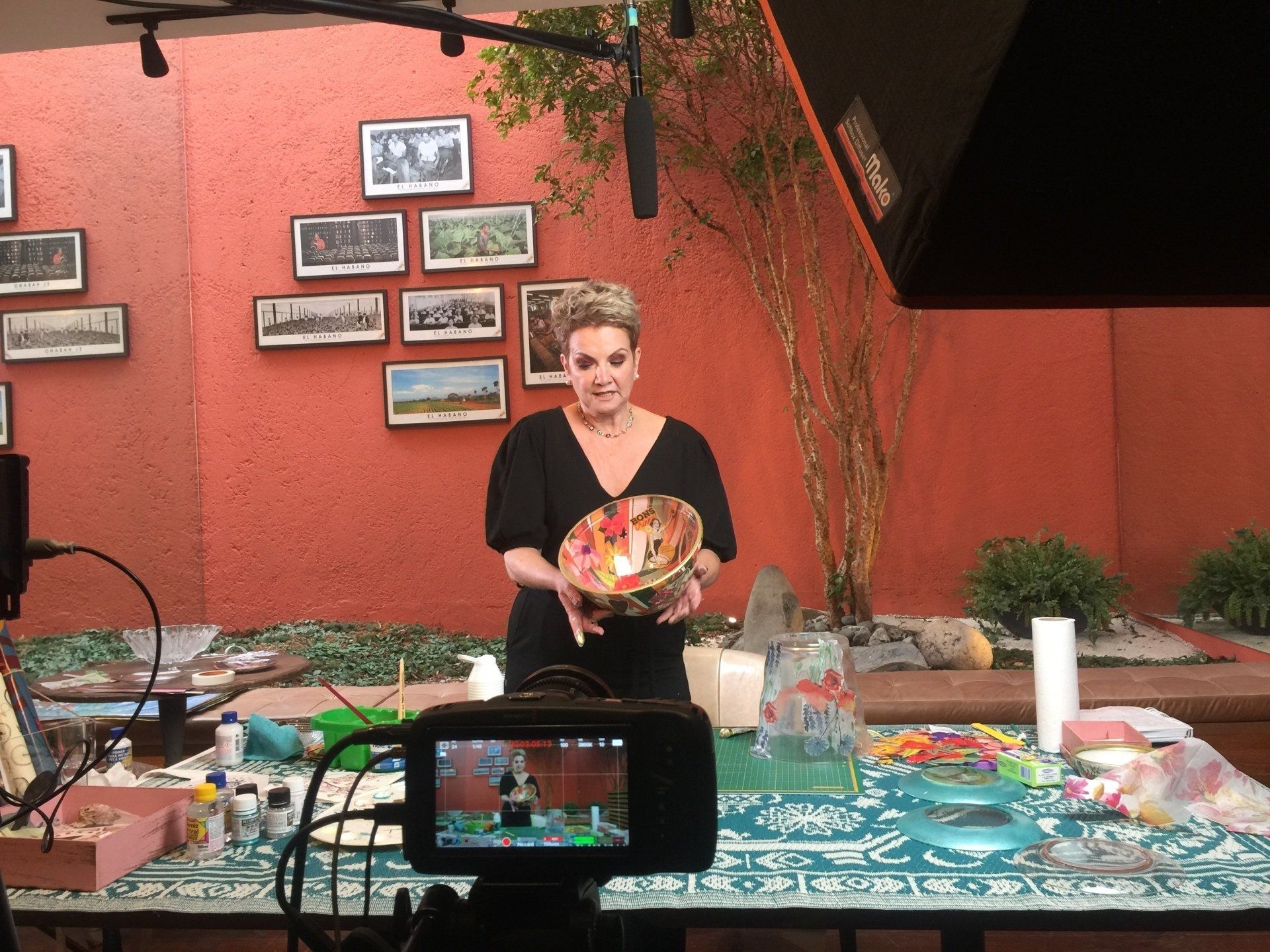 Uma mulher está segurando uma tigela na frente de uma câmera.