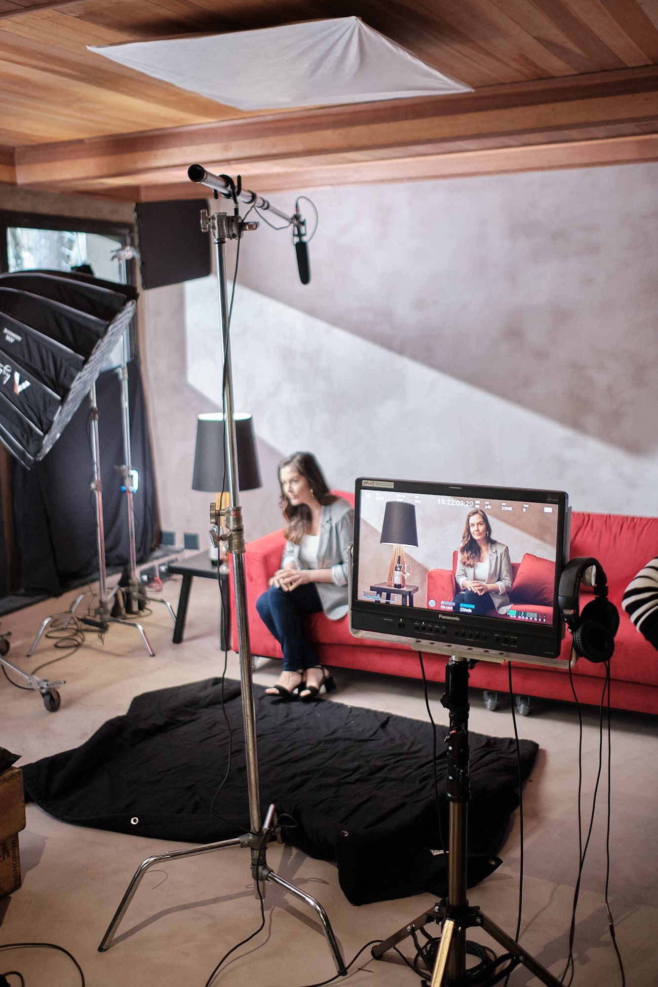Uma mulher está sentada em um sofá vermelho em frente a uma televisão.