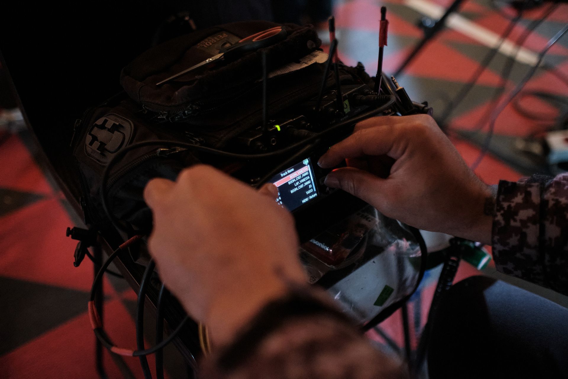 Mãos ajustando a tela e os controles de um dispositivo, possivelmente um equipamento de áudio.