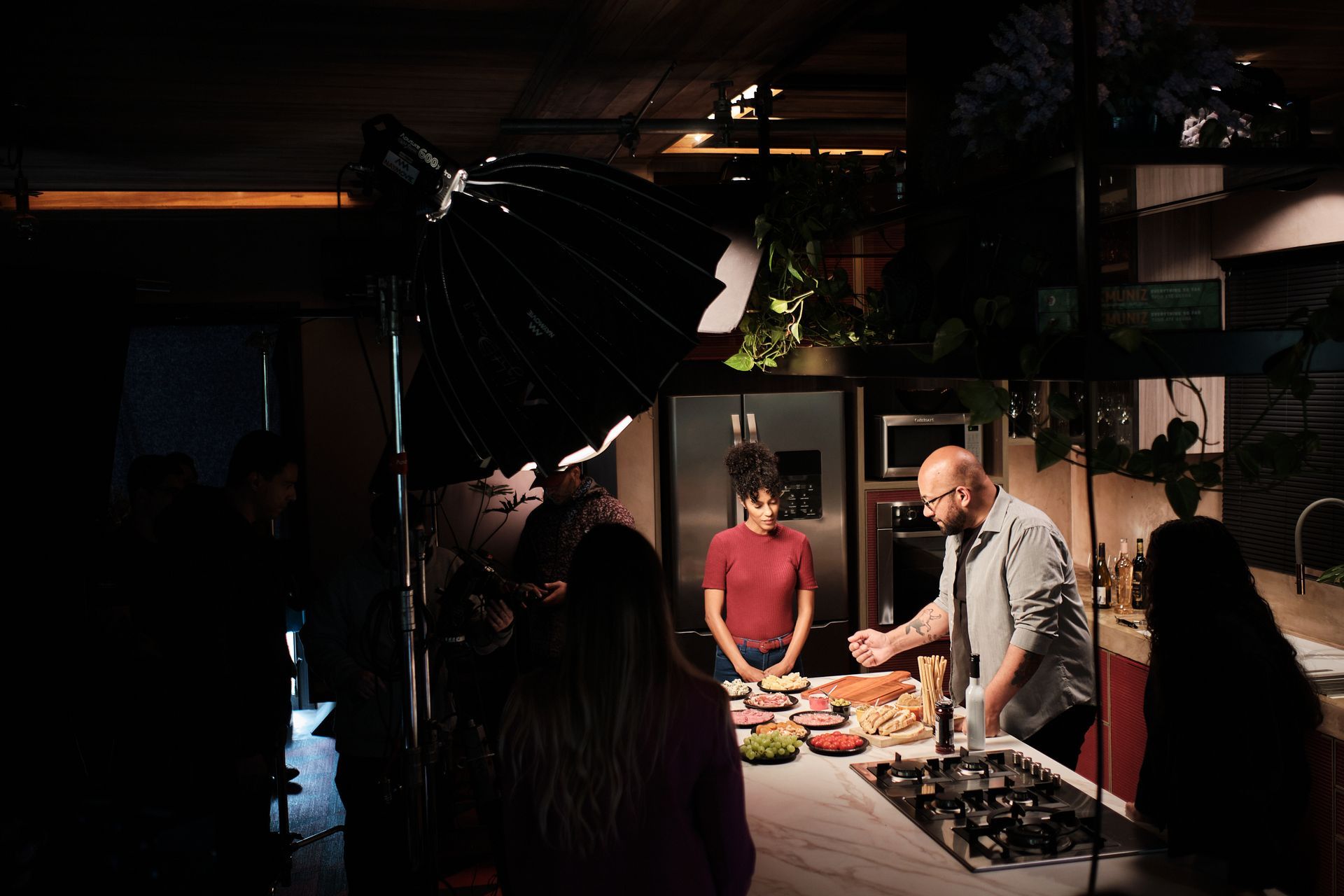 Um homem está em uma cozinha preparando comida enquanto uma mulher observa.