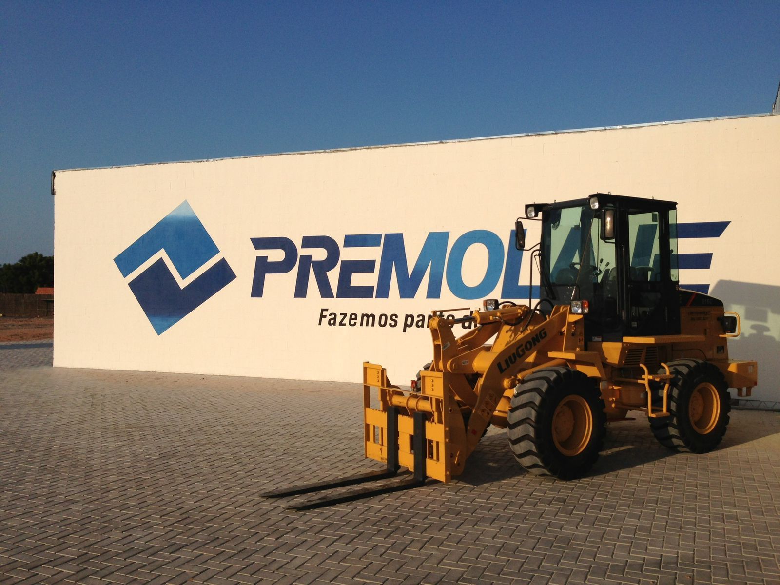 A yellow forklift is parked in front of a wall that says premolate