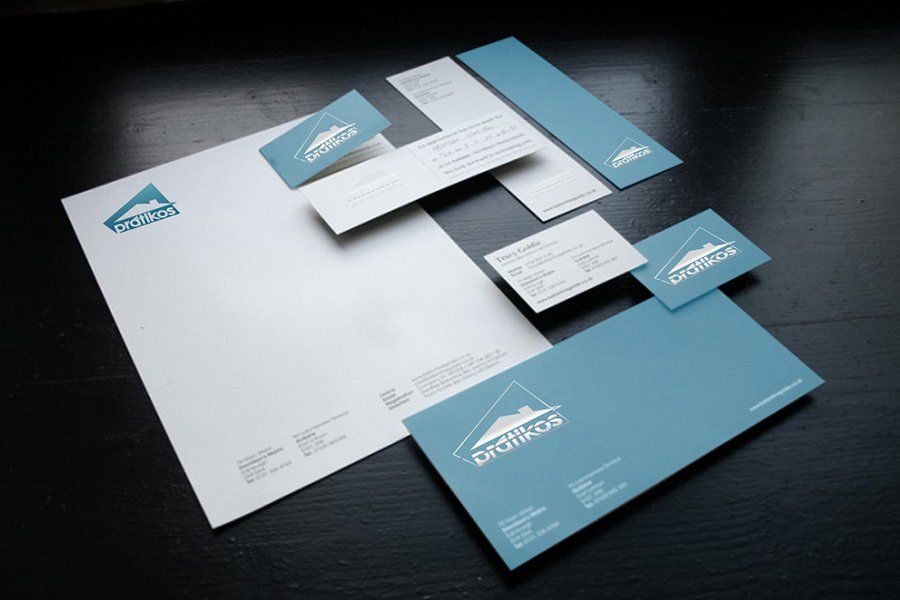 Um conjunto de cartões de visita, envelopes e um papel timbrado sobre uma mesa.