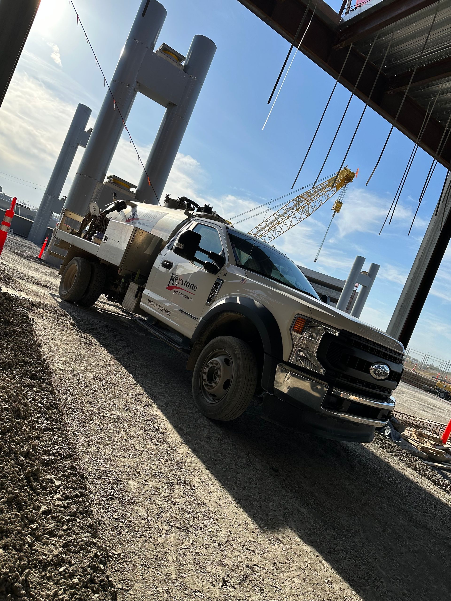 A white truck is parked on a gravel road in a construction site.