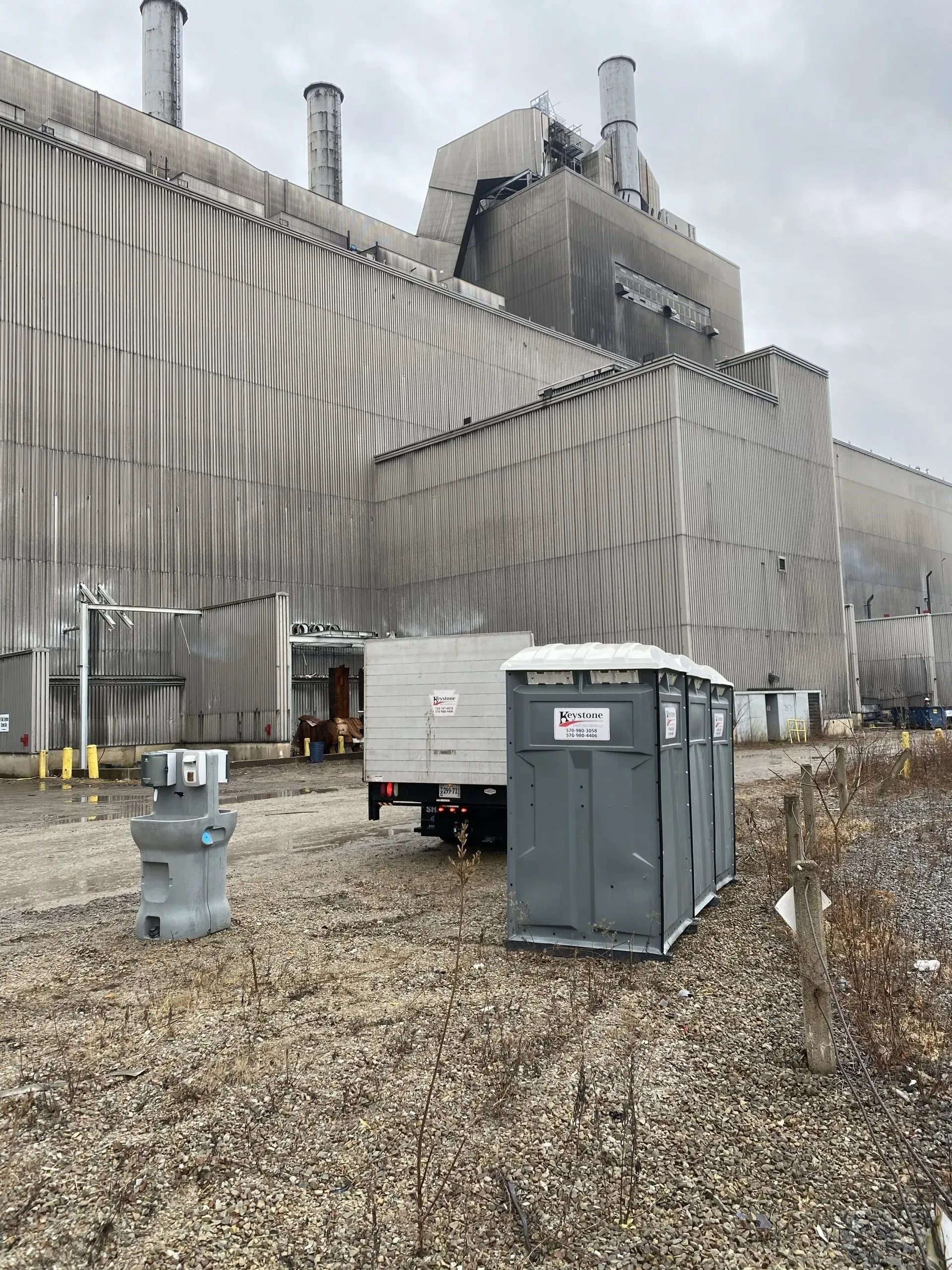 A portable toilet is parked in front of a large building.
