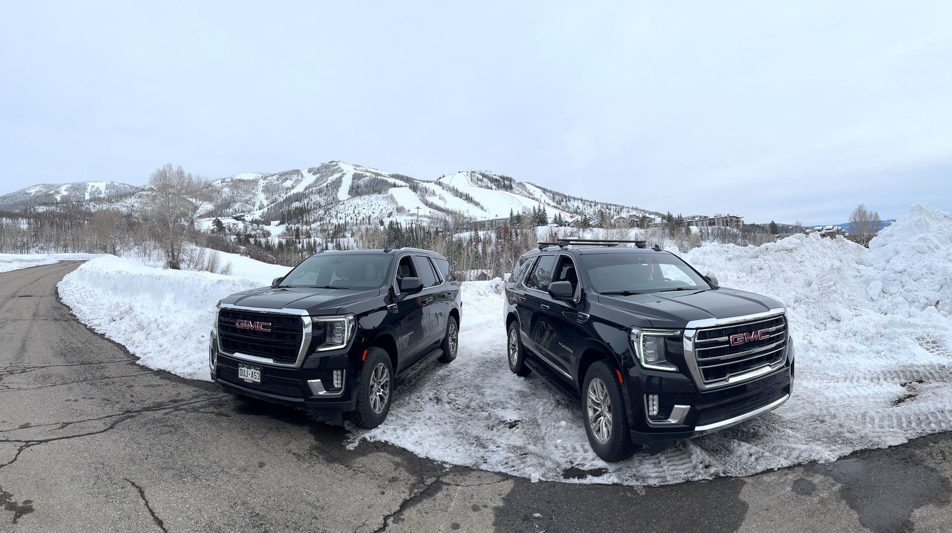 Two gmc trucks are parked next to each other in the snow.