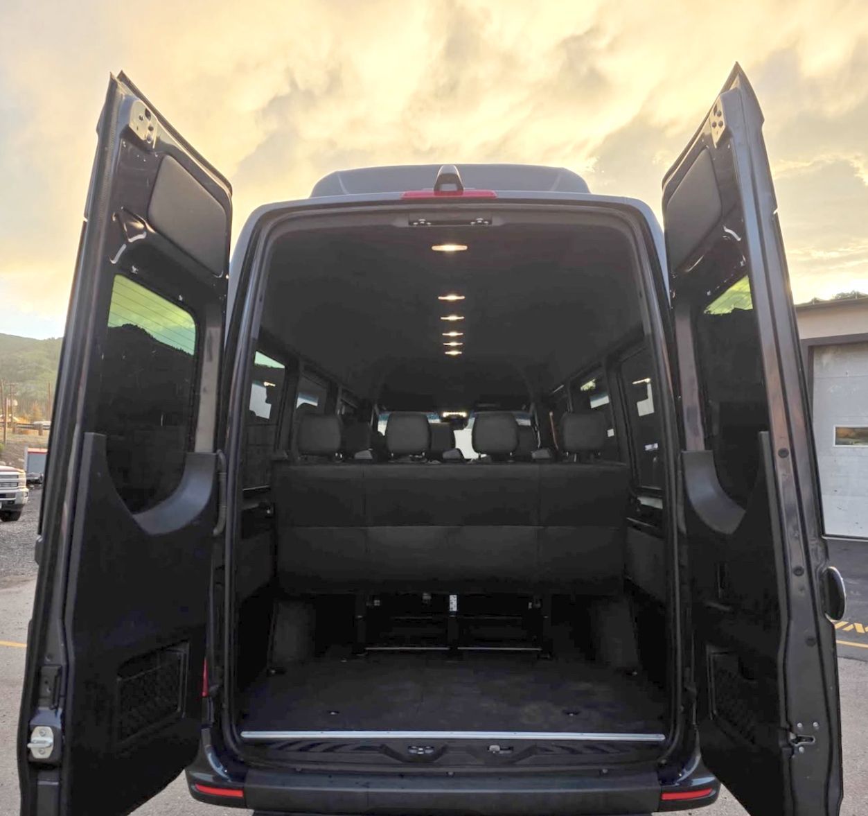 A 15 passenger van view from outside into the back of van showing luggage space and seats.